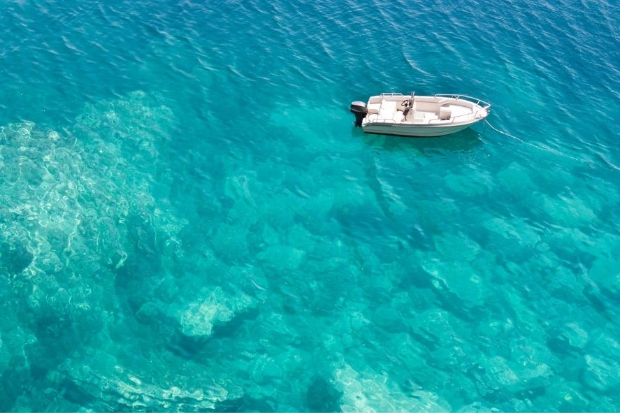 a small white boat floating on patong beach